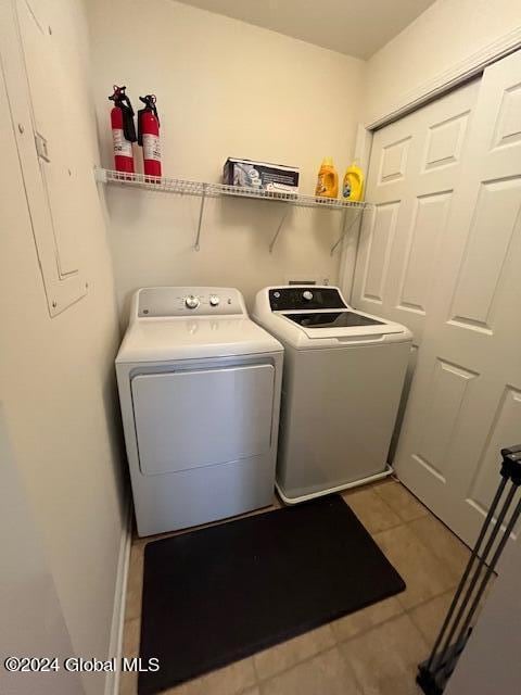 laundry area with washing machine and clothes dryer, electric panel, and light tile patterned floors