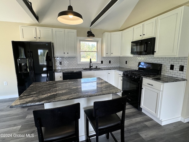 kitchen with a sink, black appliances, vaulted ceiling, and dark wood-style flooring