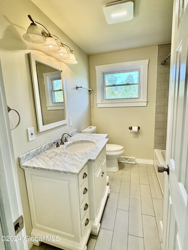 bathroom with visible vents, baseboards, toilet, shower / bathing tub combination, and vanity