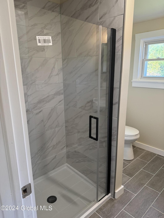 bathroom with a shower stall, baseboards, and toilet