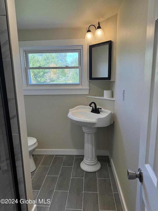 bathroom with toilet, baseboards, and wood tiled floor
