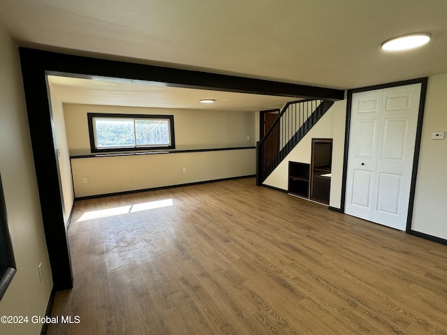 below grade area with baseboards, stairway, and wood finished floors