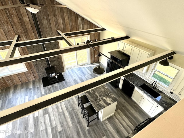 interior space with wood finished floors, a wood stove, and vaulted ceiling