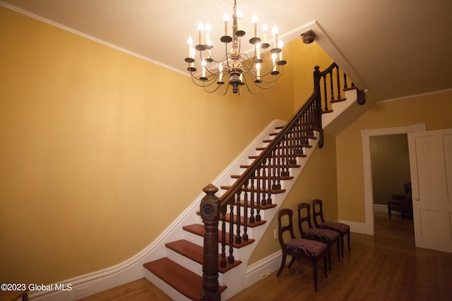 stairs featuring a notable chandelier, hardwood / wood-style floors, and crown molding