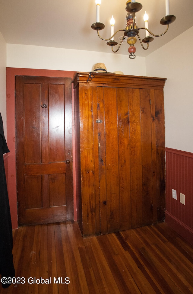 interior space featuring an inviting chandelier, wood walls, and dark hardwood / wood-style floors