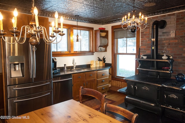 kitchen with wood-type flooring, stainless steel appliances, a wood stove, and a healthy amount of sunlight