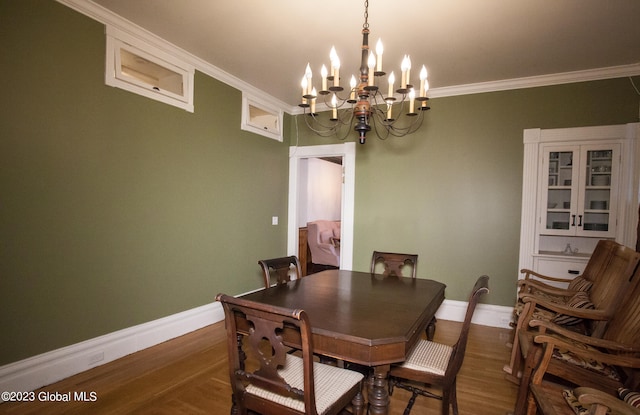 dining area featuring ornamental molding, dark wood-type flooring, and a chandelier