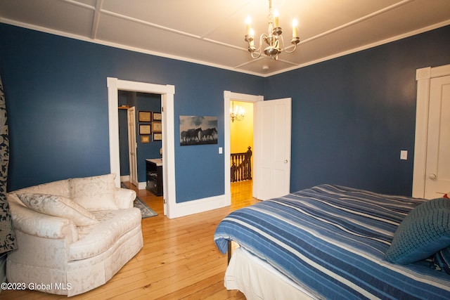 bedroom with an inviting chandelier, ornamental molding, and hardwood / wood-style floors