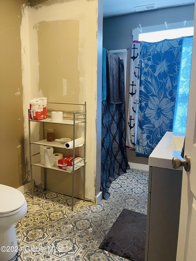 bathroom with tile patterned flooring, walk in shower, vanity, and toilet