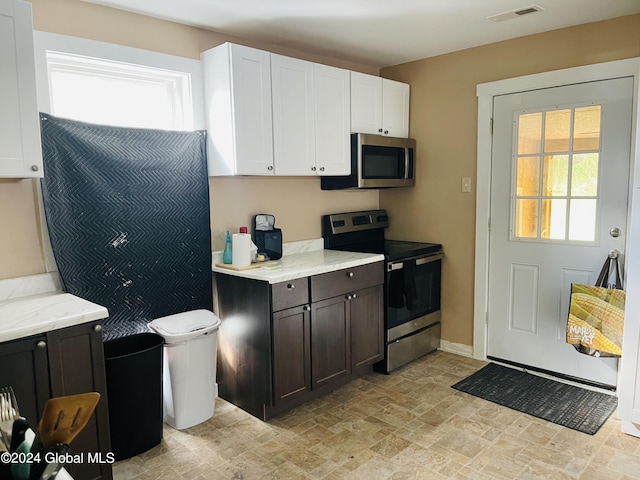 kitchen featuring dark brown cabinets, appliances with stainless steel finishes, light stone counters, and white cabinetry