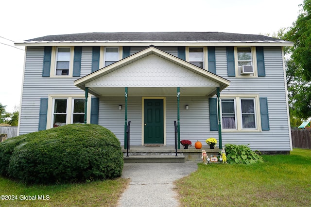 view of front facade with cooling unit, covered porch, and a front yard