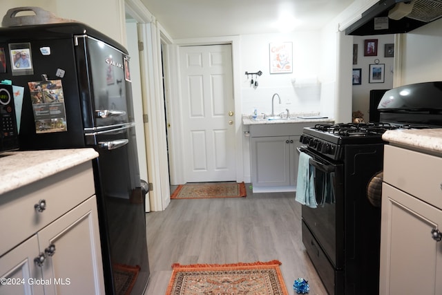 kitchen featuring ventilation hood, black appliances, light hardwood / wood-style floors, and white cabinets