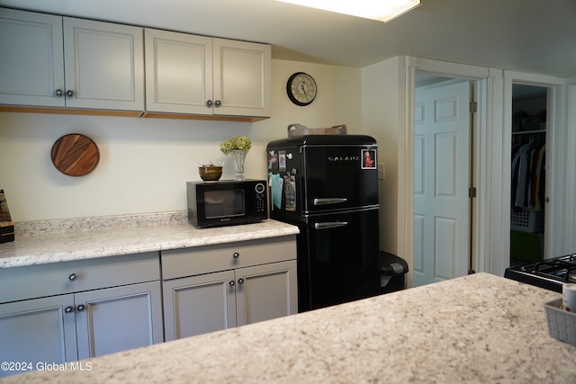 kitchen with black appliances and light stone counters