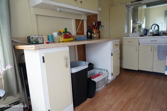 kitchen with sink, light hardwood / wood-style floors, kitchen peninsula, and white cabinetry