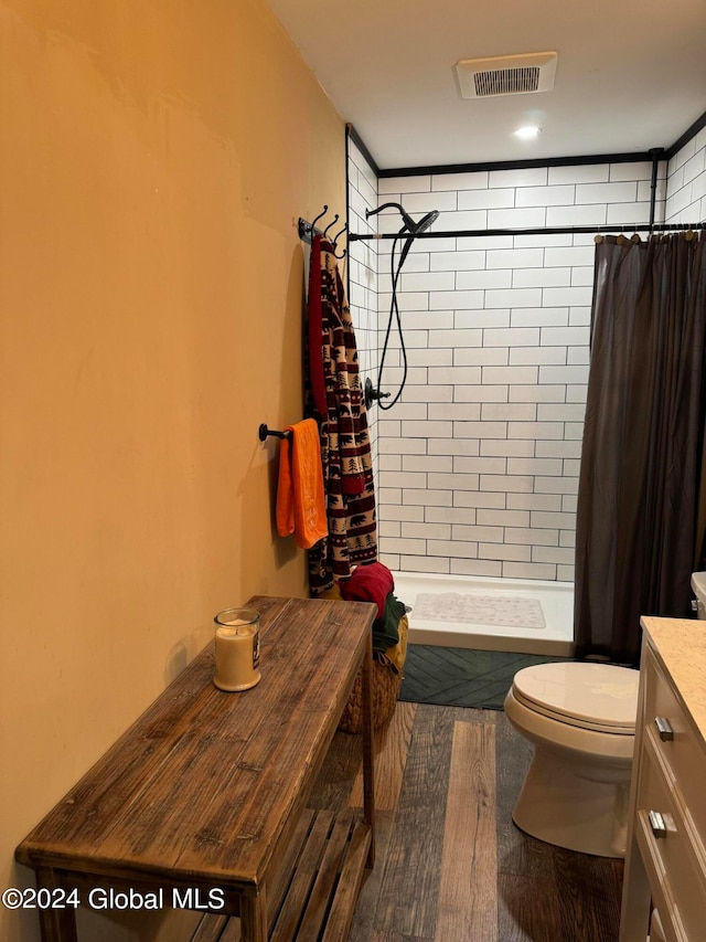 bathroom with visible vents, a shower stall, toilet, wood finished floors, and vanity