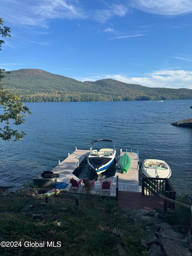 view of dock with a water and mountain view and a wooded view