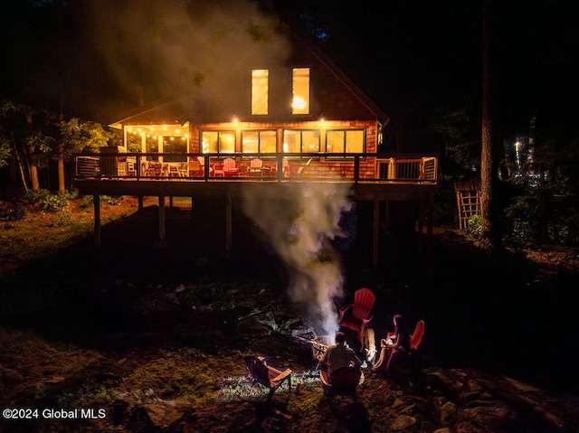 back of house at night with a deck