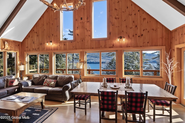 dining area featuring wooden walls, an inviting chandelier, wood finished floors, and high vaulted ceiling