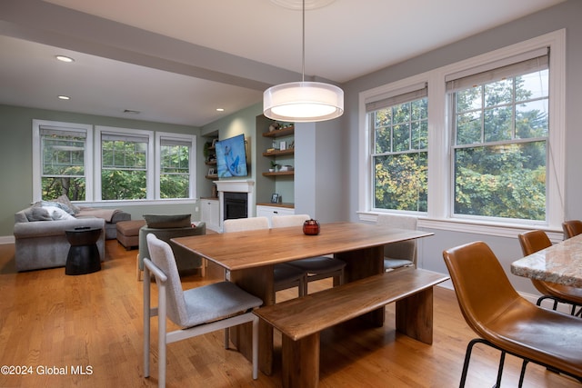 dining area with a fireplace, recessed lighting, a wealth of natural light, and light wood finished floors