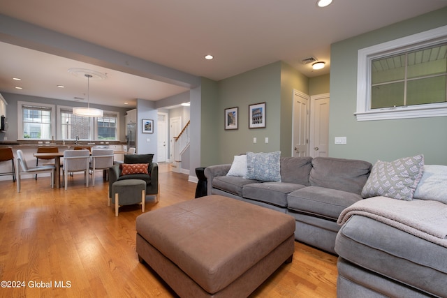 living area with visible vents, light wood finished floors, baseboards, recessed lighting, and stairway