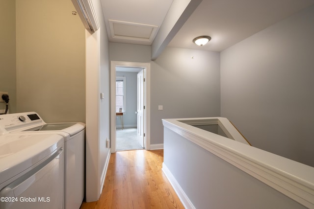 laundry room featuring baseboards, laundry area, attic access, light wood-style floors, and separate washer and dryer