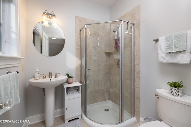 bathroom featuring toilet, a sink, baseboards, and a shower stall