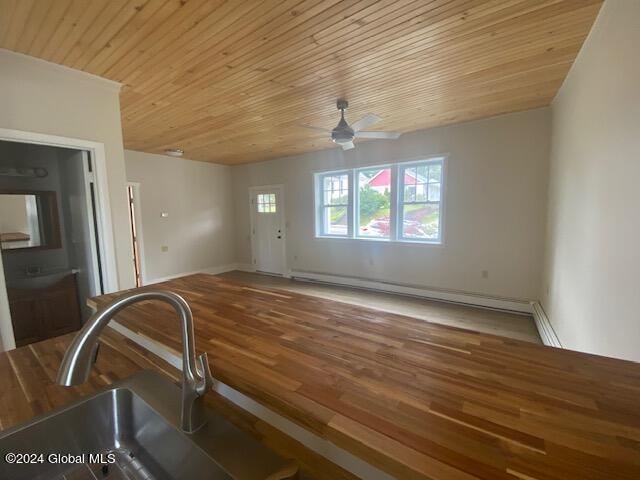 interior space featuring ceiling fan, baseboard heating, hardwood / wood-style flooring, and sink