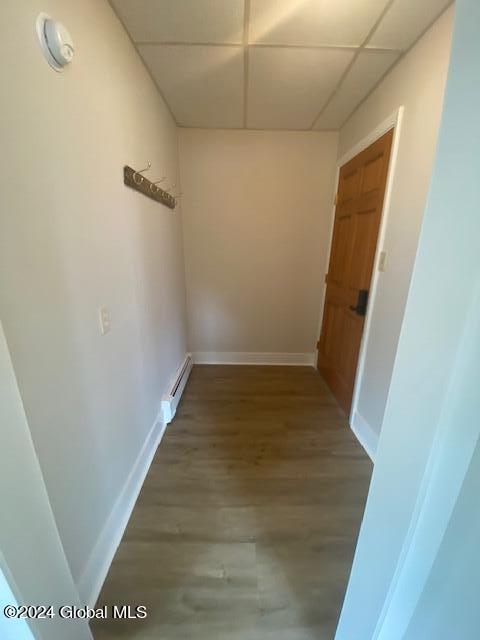 hall with hardwood / wood-style flooring, a paneled ceiling, and a baseboard heating unit