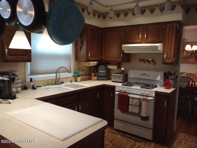 kitchen with dark parquet floors, white gas stove, dark brown cabinetry, and sink