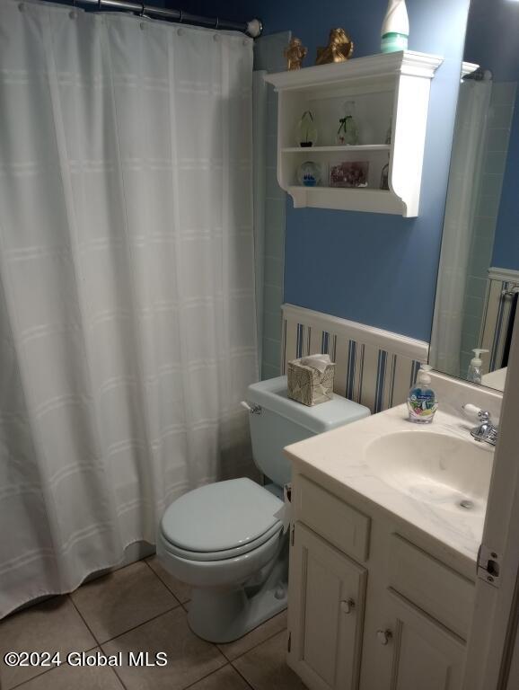 bathroom featuring curtained shower, vanity, toilet, and tile patterned floors