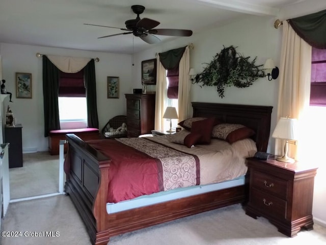 bedroom with ceiling fan, beamed ceiling, and light carpet