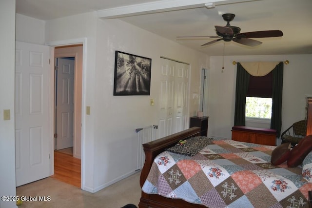 bedroom featuring a closet, light colored carpet, baseboards, and ceiling fan