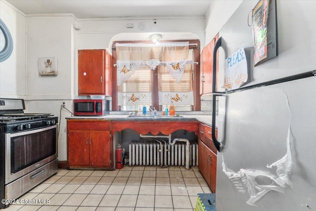 kitchen with sink, stainless steel appliances, light tile patterned floors, and radiator heating unit