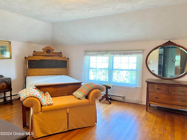 bedroom featuring a baseboard radiator, hardwood / wood-style floors, a textured ceiling, and lofted ceiling