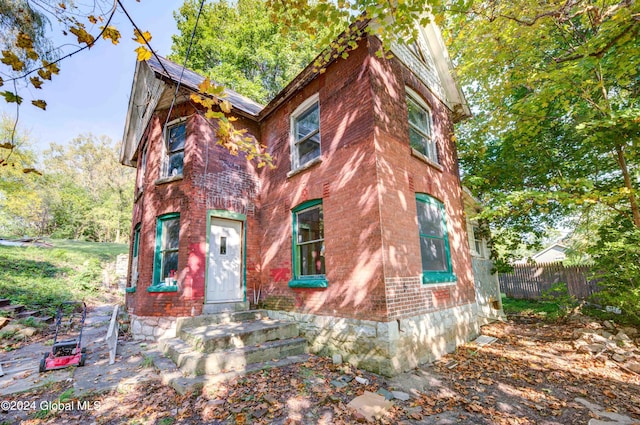 view of front facade with brick siding and fence