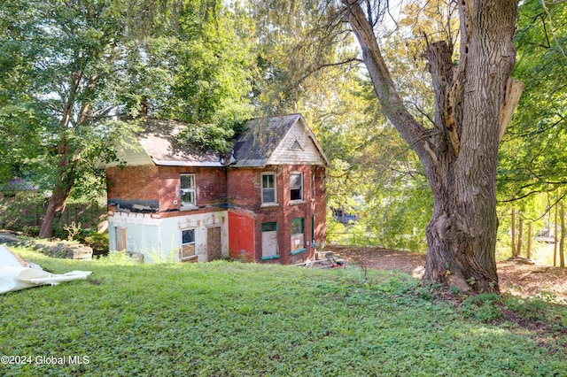 rear view of house featuring a lawn and brick siding