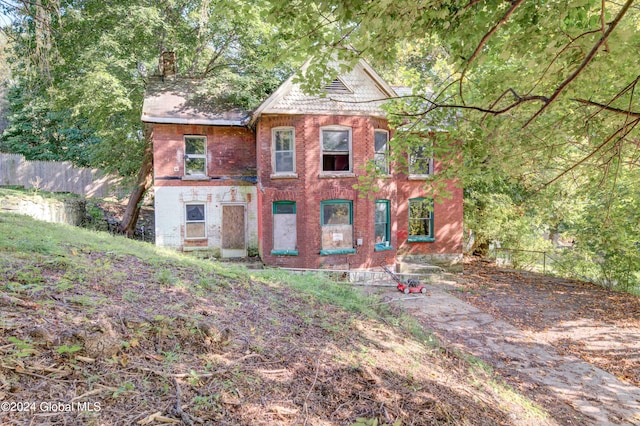 view of front of home featuring a chimney, fence, and brick siding