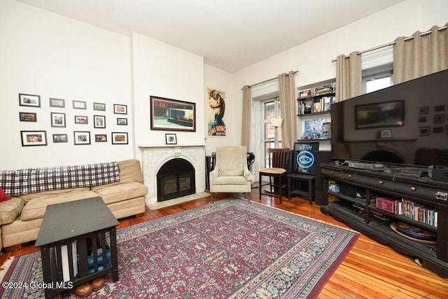 living room with a fireplace with flush hearth, wood finished floors, and plenty of natural light