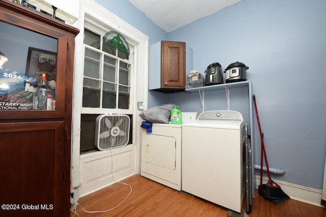 clothes washing area featuring washer and clothes dryer, cabinets, and light wood-type flooring