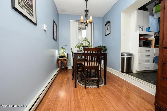 dining room featuring a baseboard radiator, baseboards, a notable chandelier, and light wood-style flooring