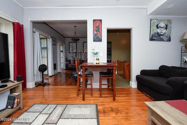 living area with baseboards, ornamental molding, and wood finished floors