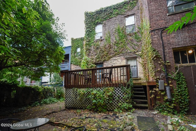 rear view of property with brick siding, stairs, and a deck