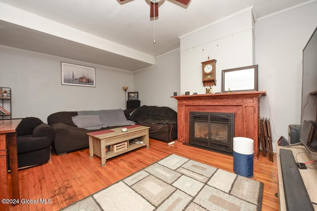 living area with a ceiling fan, crown molding, a glass covered fireplace, and wood finished floors