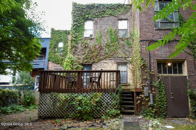 rear view of house with a wooden deck, brick siding, and stairs