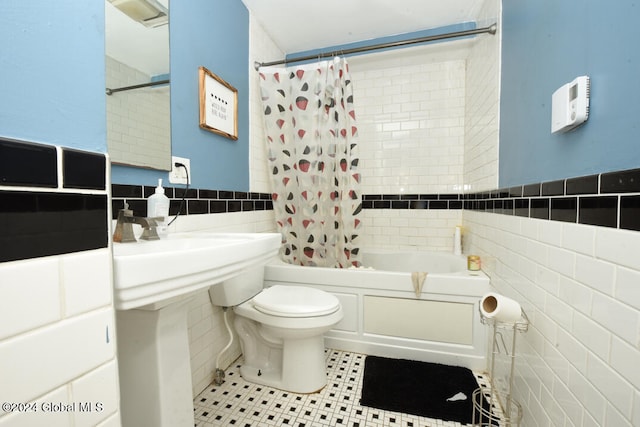 bathroom with tile walls, shower / tub combo, and toilet