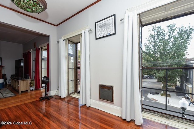 entryway with baseboards, heating unit, wood finished floors, and ornamental molding