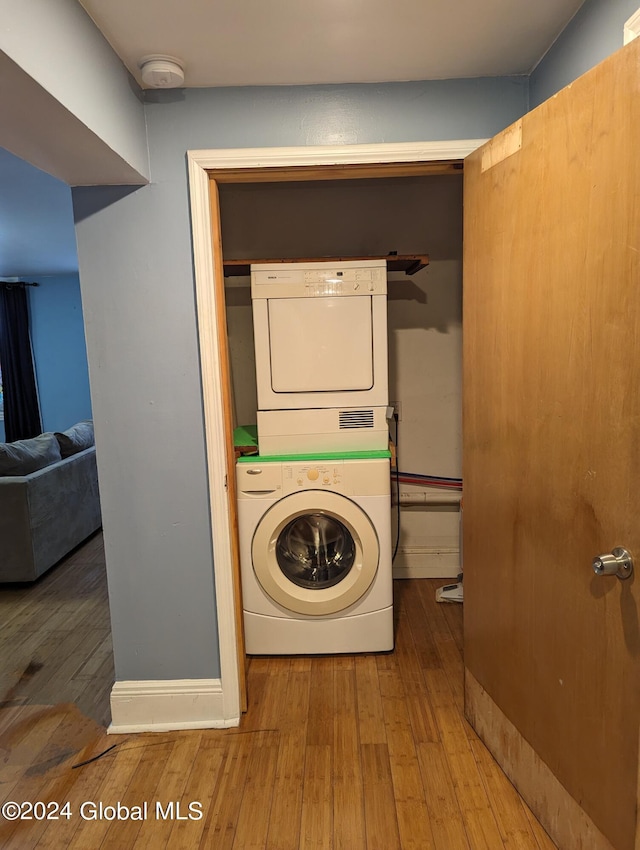 clothes washing area with stacked washing maching and dryer and wood-type flooring