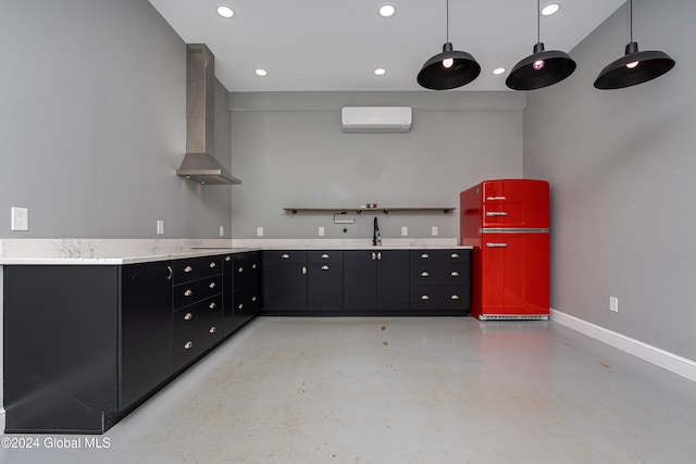 kitchen featuring fridge, wall chimney exhaust hood, a wall unit AC, and hanging light fixtures