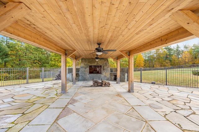 view of patio featuring an outdoor stone fireplace and ceiling fan