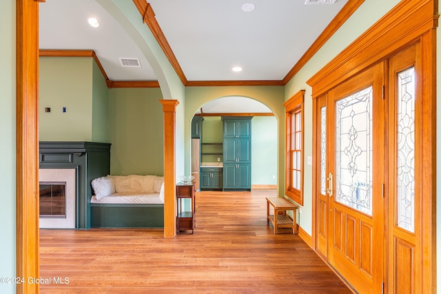 entrance foyer with ornamental molding, plenty of natural light, and light hardwood / wood-style floors